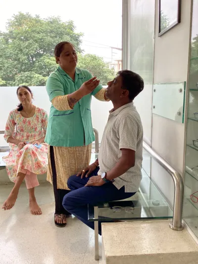 A nurse putting eye drops in for a patient before examination